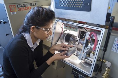 a female engineer working with a sophisticated piece of machinery in a lab.