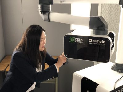 A researcher carefully working with a piece of advanced scientific equipment labeled 'DENS solutions' and 'climate GAS SUPPLY SYSTEM.'