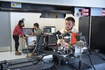 A researcher works intently on a high-precision scientific instrument in a laboratory setting.