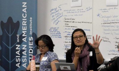 Two individuals are engaged in a discussion at an event hosted by the Asian and Asian American Studies Institute.