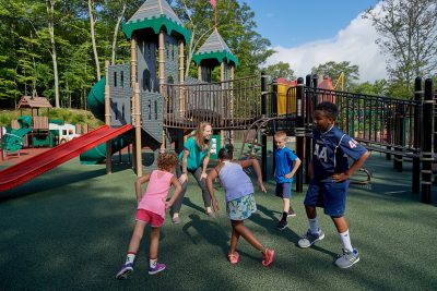 Lindsay Distefano, associate professor of kinesiology,shows children how to exercise on a playground at the Mansfield Community Center on Aug. 3, 2018. (Peter Morenus/UConn Photo)