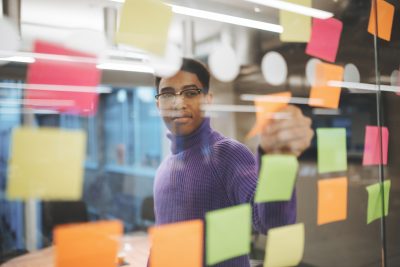 Asian businesswomen use post-it notes on glass walls to write strategy business plans to development grow to success