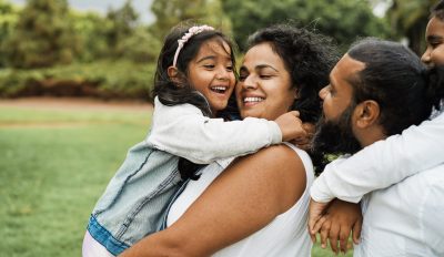 Happy indian family having fun outdoor - Hindu parents laughing with their children at city park