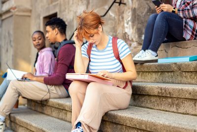 Female student sits on the stairs studying.