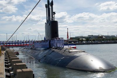 A submarine in port with it's crew standing atop it